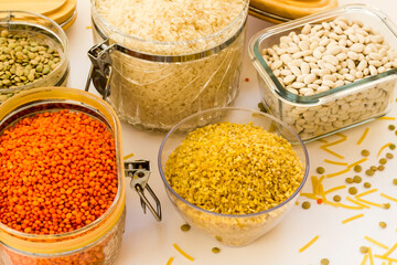 Uncooked dry cereal food group in glass containers on white,above view