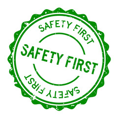 Grunge green safety first word round rubber seal stamp on white background