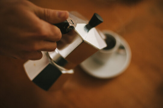 Percolator pouring black espresso into espresso cup