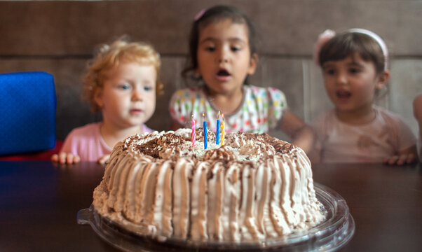 Little girls blow out candles on a birthday cake