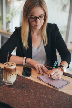 Woman writing her diary in a coffee shop