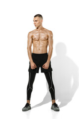 Fototapeta premium Posing. Stylish young male athlete practicing on white studio background, portrait with shadows. Sportive fit model in works out in motion and action. Body building, healthy lifestyle, style concept.