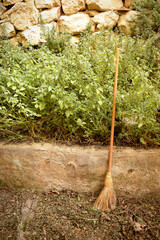 Old broom in a rustic setting with plants and field materials