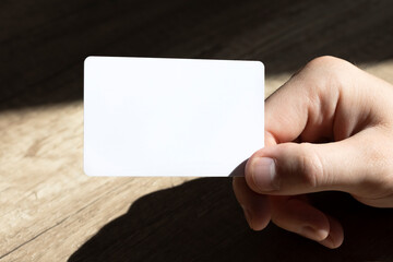 Obraz premium Mockup business cards on man's hands on a wooden background.