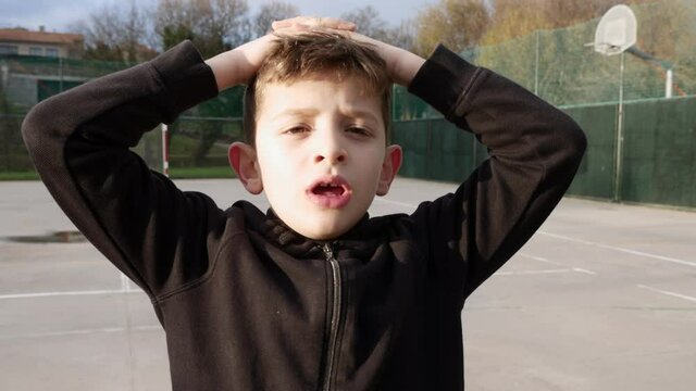 video of a happy young boy sneezing and doing funny faces, outdoors