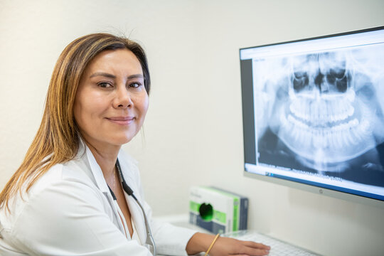 A dentist looking at x-rays in a computer