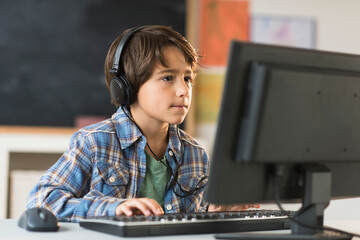 Schoolboy (6-7) using computer in classroom