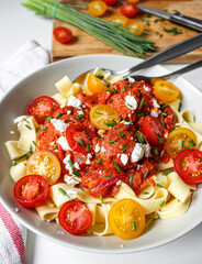 Tomato sauce pasta topped with cherry tomatoes on white plate over a white table. Food styling and photography. 