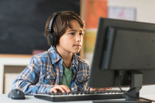 Schoolboy (6-7) using computer in classroom