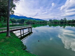 Naklejka na ściany i meble land scape with cloud on sky, mountain, lake and walking bridge in the lake. Also big tree on the left of photo.