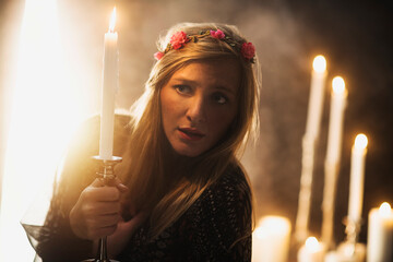 Sorceress holding candle in dark room