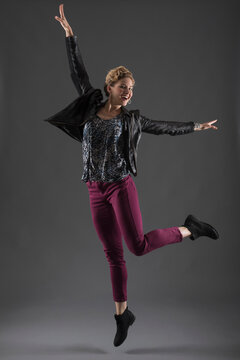 Studio shot of cheerful woman jumping with arms raised