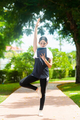 Portrait of Beautiful young asian woman enjoying online shopping on tablet while practicing yoga in morning park.