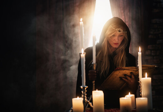 Sorceress reading book in dark room