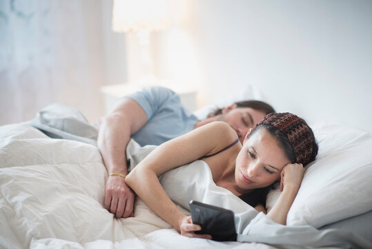 Couple in bed, Man sleeping, Woman using tablet pc
