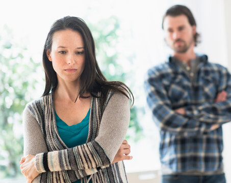 Sad woman with arms crossed, man in background