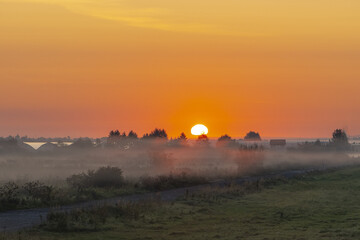 Autumn early morning, fog creeps over the ground, sunrise in the countryside over the field