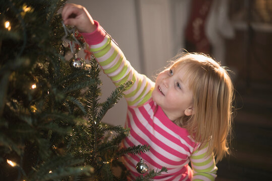 Girl (4-5) decorating christmas tree