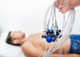 Doctor holding ECG electrodes for heart diagnostic over mature man. Medical equipment for...