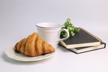 Croissant with hot coffee with 2 black books on white background