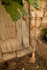 Old broom next to a weathered wooden door in a rural setting