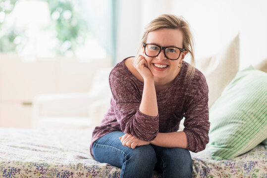 Portrait Of Smiling Young Woman Sitting On Bed