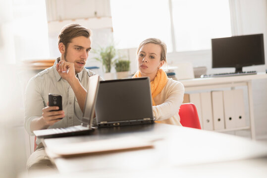 Young man and woman working together with laptop in office