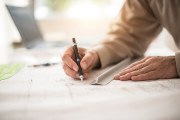 Close up of architect's hands drawing on blueprint