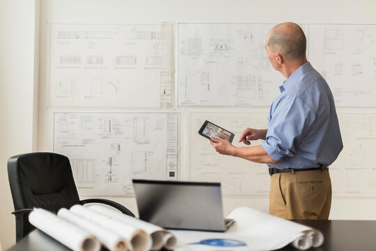 Mature architect looking at blueprints in office