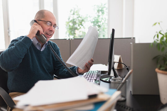 Mature businessman using landline phone in office