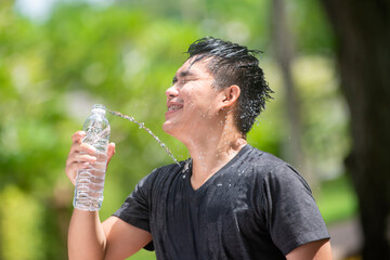 Young asian man fitness runner drinking and splashing water in his face. Funny image of handsome male refreshing during workout. Copy space