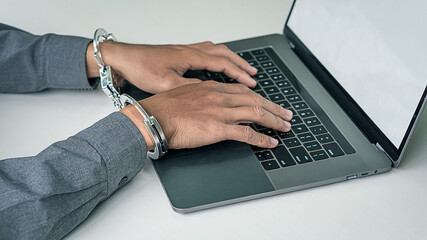 Locked hands, handcuffs, and playing laptop computers on the table.