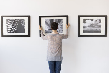Woman hanging photographs in art gallery