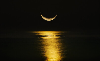 Crescent moon reflecting in sea