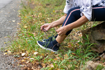 Cropped view of sporty elderly woman tying sport shoes. Active outdoor lifestyle