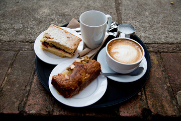 Flat White Coffee and two pieces of Cake on a Brick Path