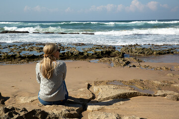 Mujer sentada en la orilla de la playa.