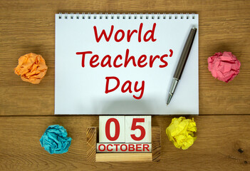 White note with inscription 'World Teachers' Day' on beautiful wooden table, colored paper, metalic pen and wooden calender with date october 05. Concept.