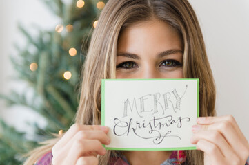 Young woman holding greeting card for christmas