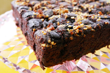 Selected focused on the chocolate cake. Rectangular in shape. Crushed almonds are sprinkled on it. Has been cut into small cubes to make it easier to eat.