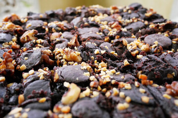 Selected focused on the chocolate cake. Rectangular in shape. Crushed almonds are sprinkled on it. Has been cut into small cubes to make it easier to eat.