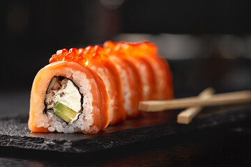 Sushi roll maki futo japanese food on a black stone plate in the hands of a waiter. Close up