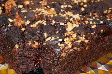 Selected focused on the chocolate cake. Rectangular in shape. Crushed almonds are sprinkled on it. Has been cut into small cubes to make it easier to eat.