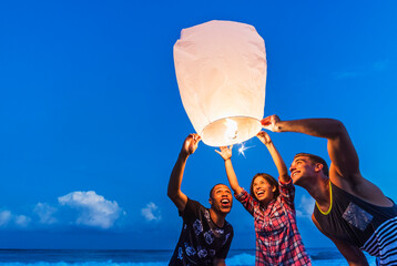 Young people with illuminated lantern on beach