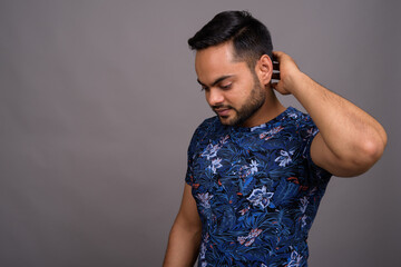Young bearded Indian man against gray background