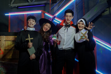 A group of Asian men and women wearing as vampire, witch, dead nun, pastor having Fun at Party in Nightclub. Celebration of Halloween
