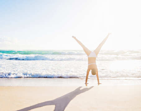 Woman doing handstand on beach