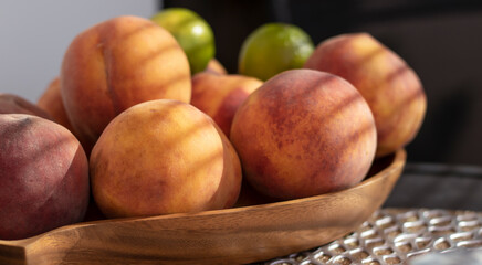 Fruit in a wooden bowl. Peach and lime on the table. Close-up.