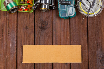 Different fishing tacles with lures and reels on wooden brown background with place for text.