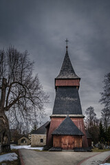 Fototapeta na wymiar Unique 17th century wooden church in Bialka Tatrzanska. Dark, moody storm clouds and dramatic sky. Tatra Mountains, Poland